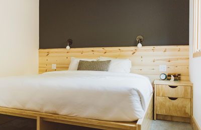 Modern wood furnishings surround neatly made bed at The Society Hotel - Bingen. Wet Planet Whitewater in Washington, Idaho, Oregon
