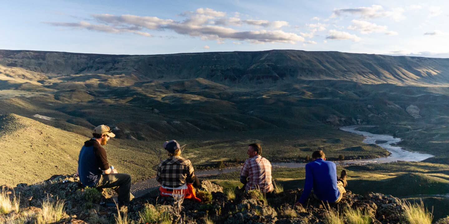 Four people sitting on a ridge overlooking the Owyhee River valley