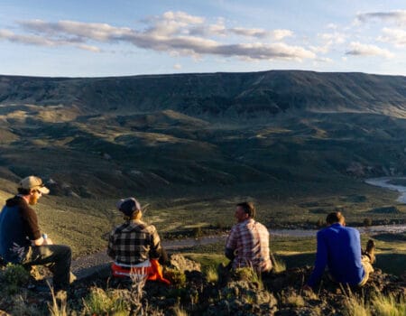 Four people sitting on a ridge overlooking the Owyhee River valley