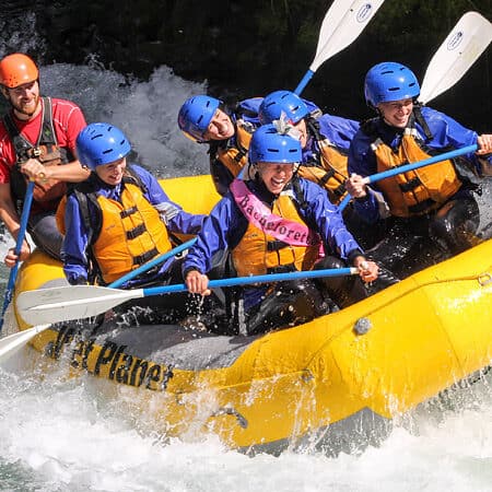 A group of women raft through Top Drop rapid, with one of them wearing a bachelorette banner.