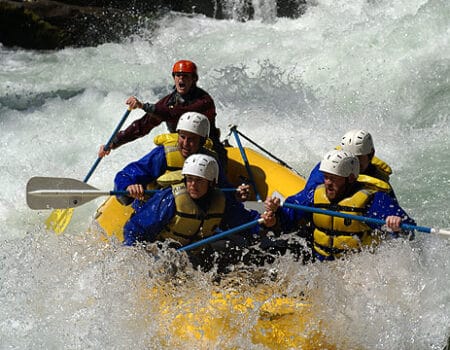A group of people going through a rapid in a raft on the Wind River