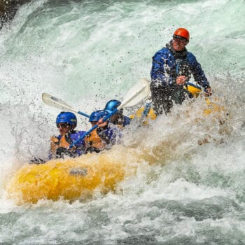 Class V rafters hold on while running Climax rapid on a Wind River rafting trip.